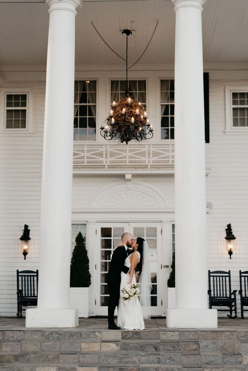 Bride and Groom Kissing at The Manor House on the porch