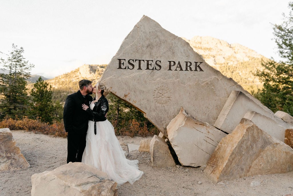 Bride and groom pose after their hermit park elopement at the estes park sign