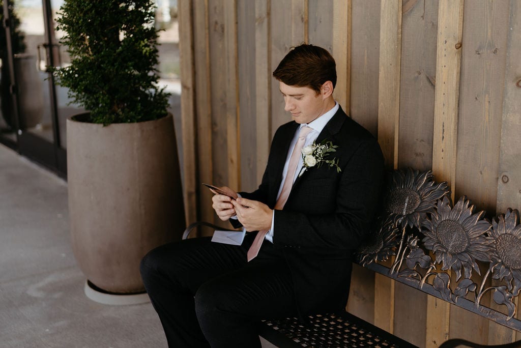 Groom sits on the porch at bonnie blues event venue and reads letter from bride