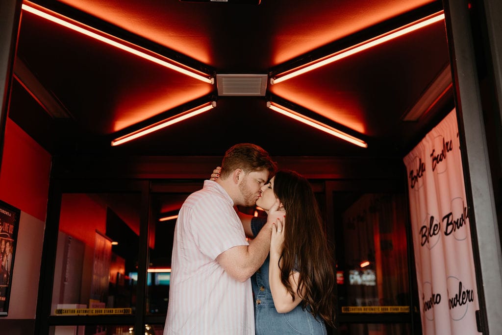 Couple kisses at the entrance of Bowlero during their bowling engagement session