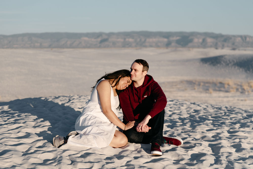 Sitting in the sunshine on a sand dune at White Sands Engagement session