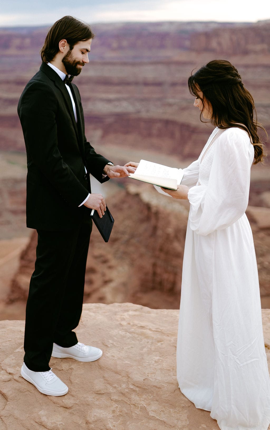 Couple exchange rings on a cliffside in moab utah elopement