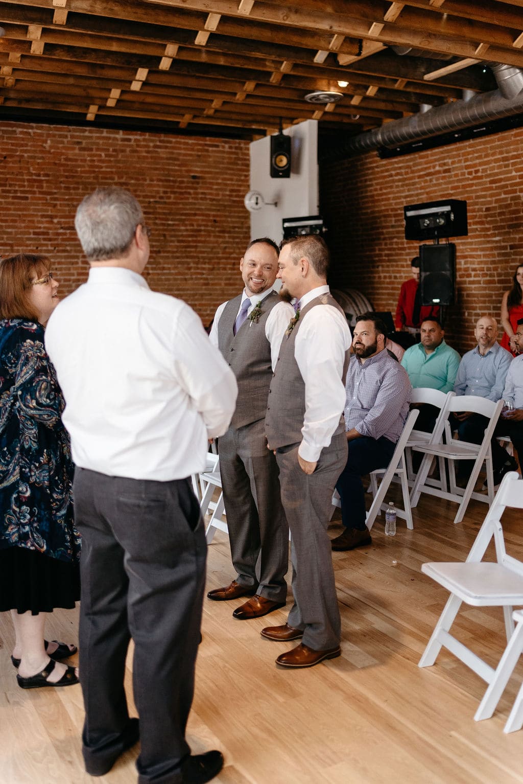 Two grooms get married and smile at each other sweetly at Wash Park Studio near Denver Colorado at their Indoor modern ceremony 