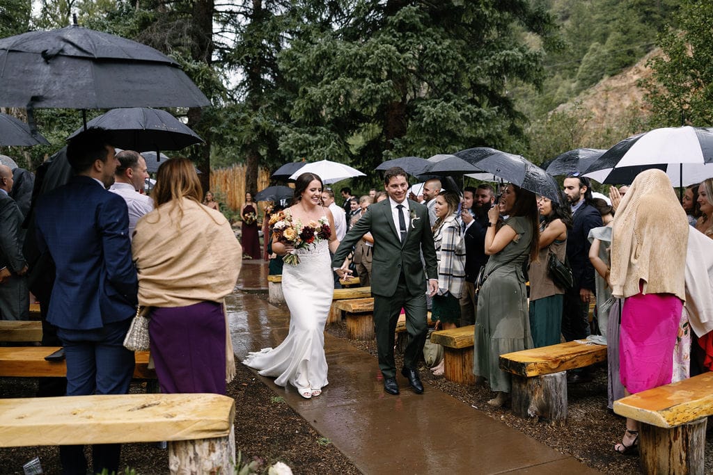 Bride and groom walk out after ceremony at Blackstone Rivers Ranch in Idaho Springs Colorado