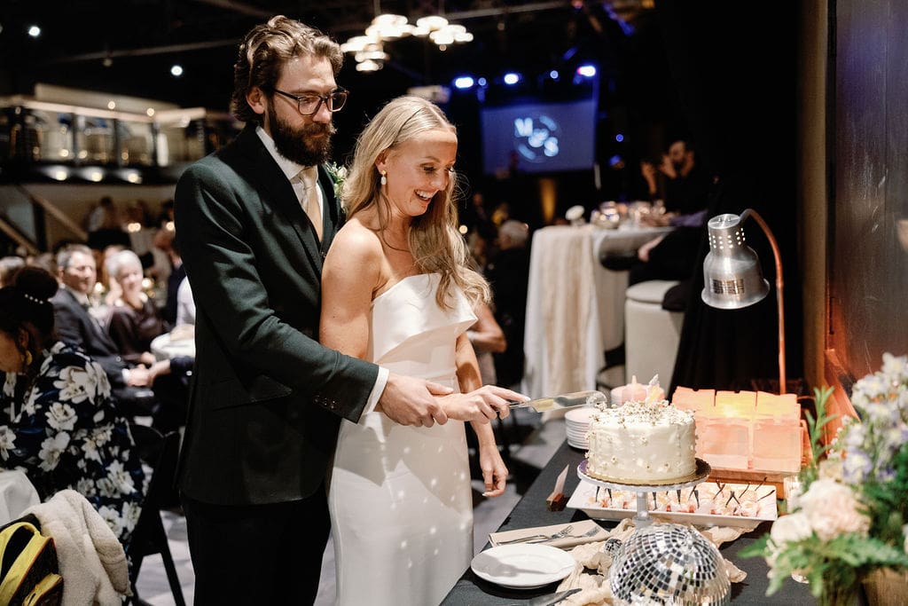 Couple cuts their wedding cake at The Rose Event Venue taken by Denver Wedding Photographer