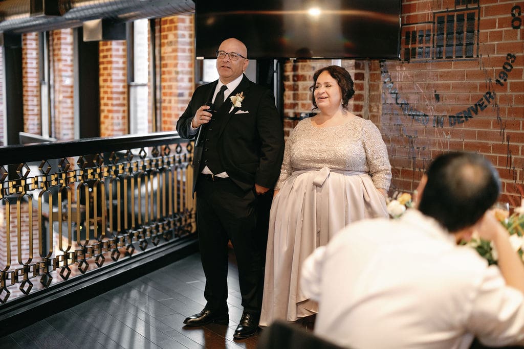 Wedding Reception taking place at Ironworks Wedding Venue in Denver and Couple and guests give a toast to welcome the night