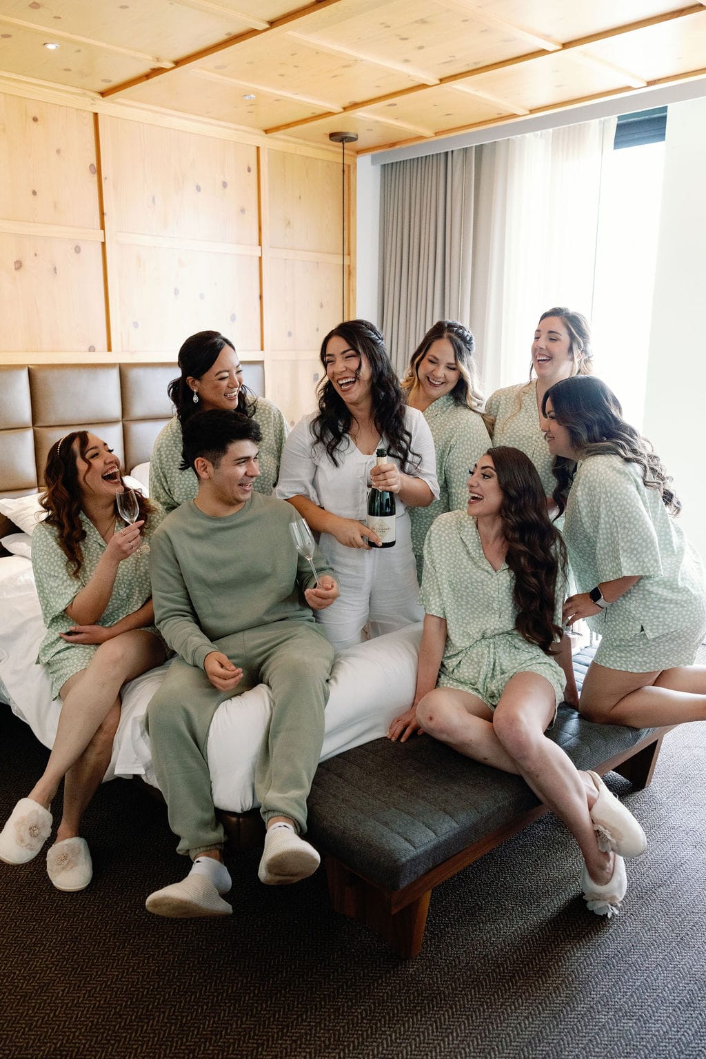 Bride and bridesmaids toast each other at limelight denver hotel room on the morning of her wedding day 