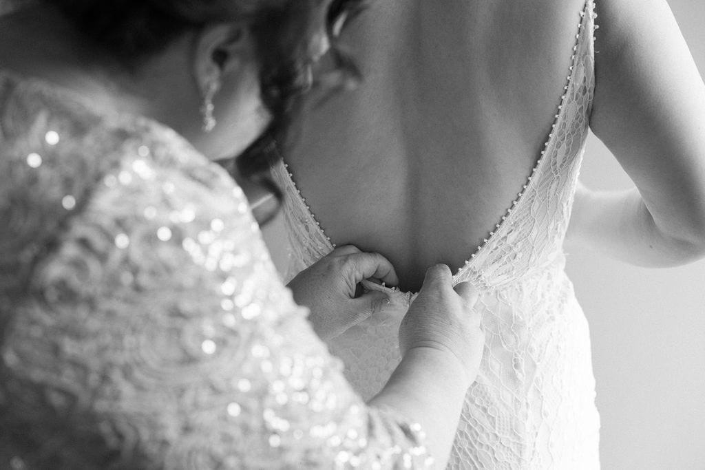 Bride puts her dress on with the help of her mom while getting ready for her wedding day in denver colorado
