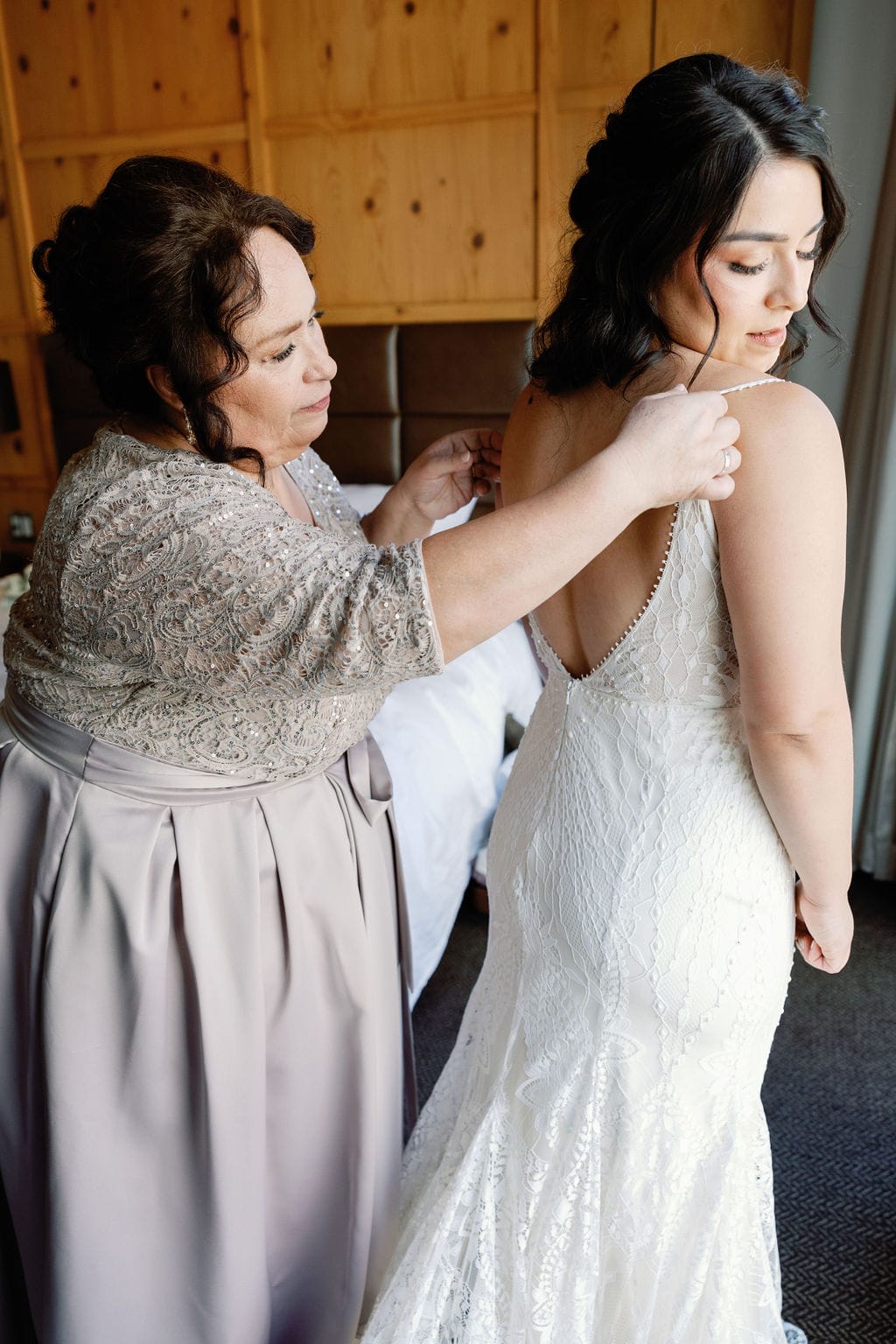 Bride puts her dress on with the help of her mom while getting ready for her wedding day in denver colorado