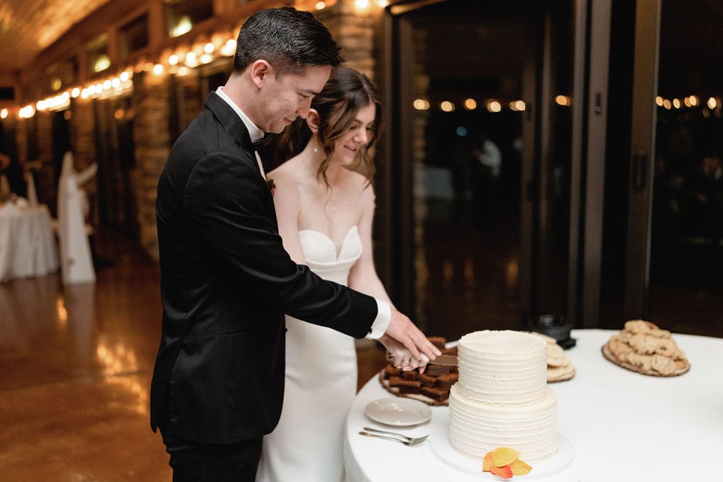 Mt Princeton Hot Springs Wedding Couple Cuts Their Wedding Cake in a beautifully lit up reception room