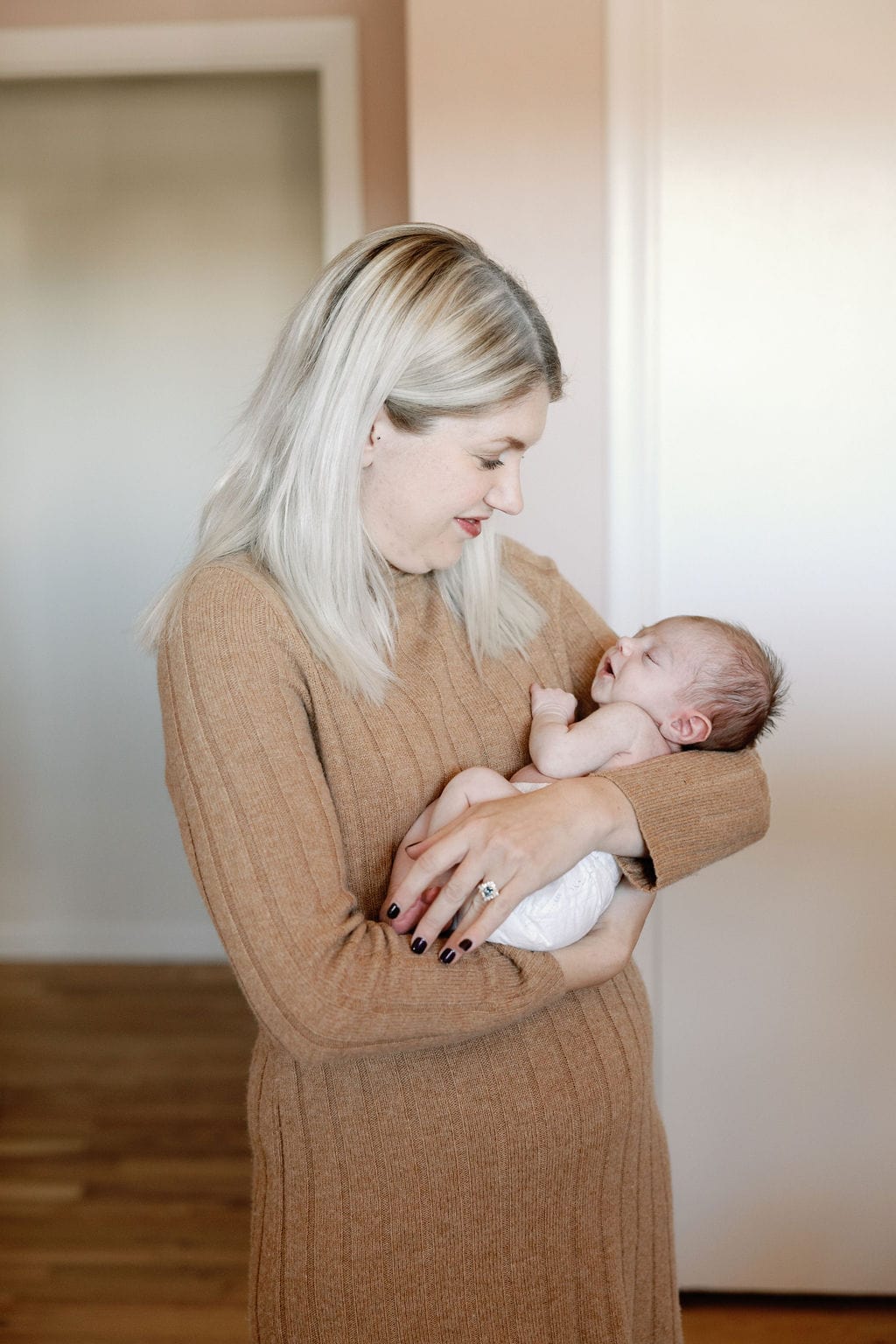 Mom holds baby in the nursery during her in home newborn session