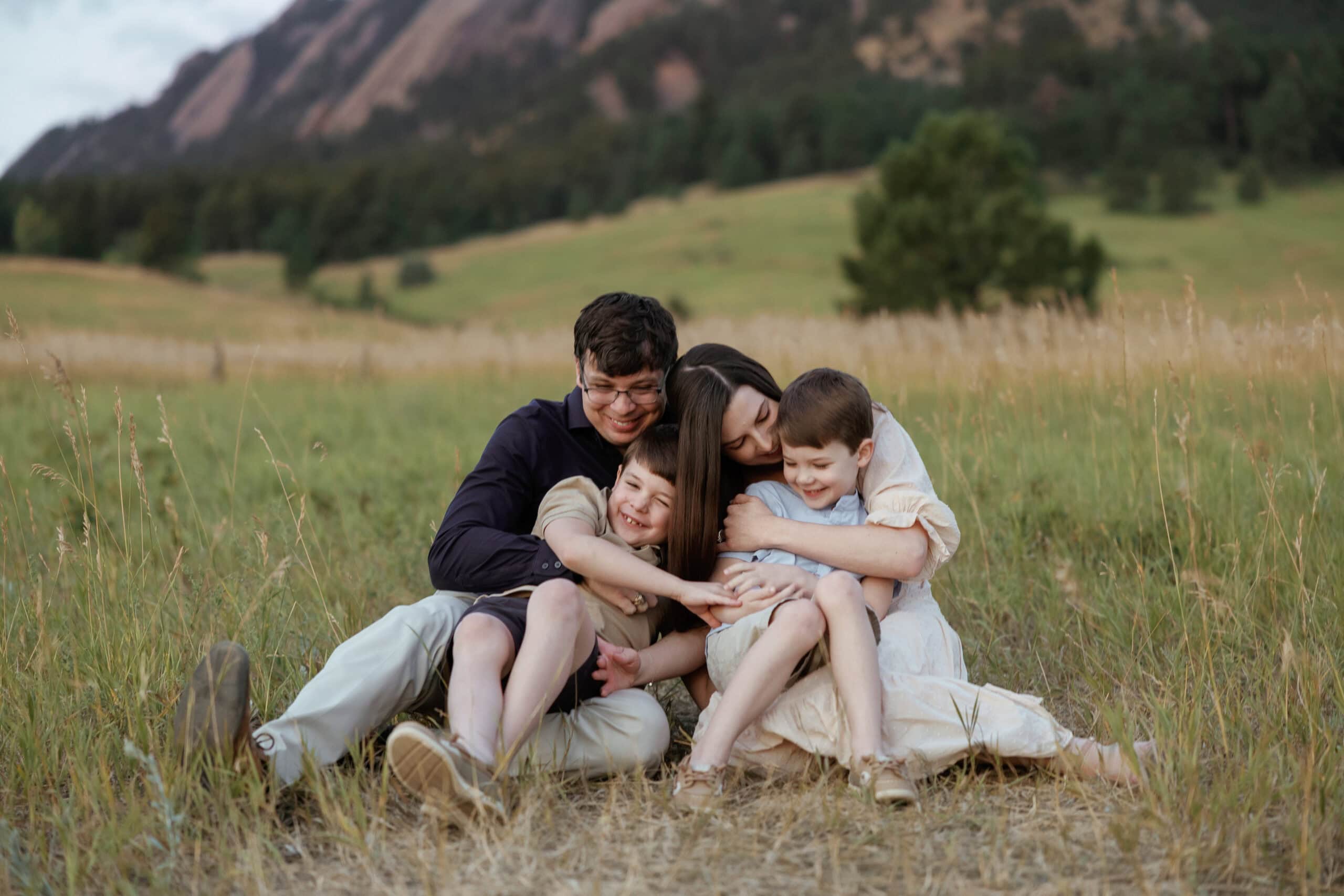 Family snuggles and tickles during their sunrise family photos at chautauqua park