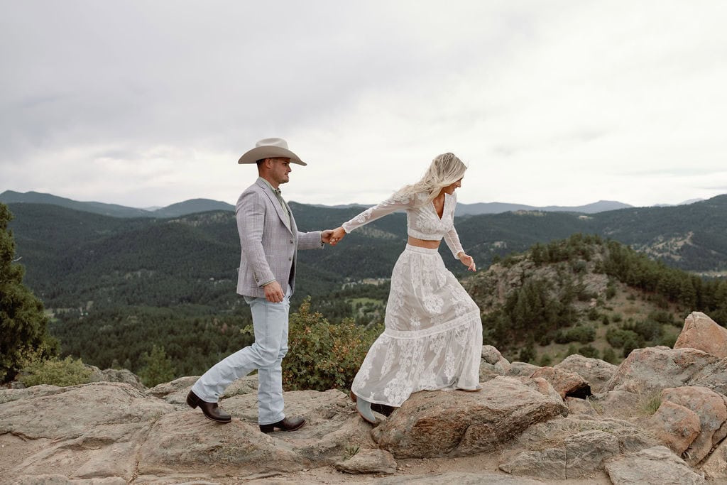 Couple explores a rocky overlook at their mountain country chic engagement session at mount falcon west