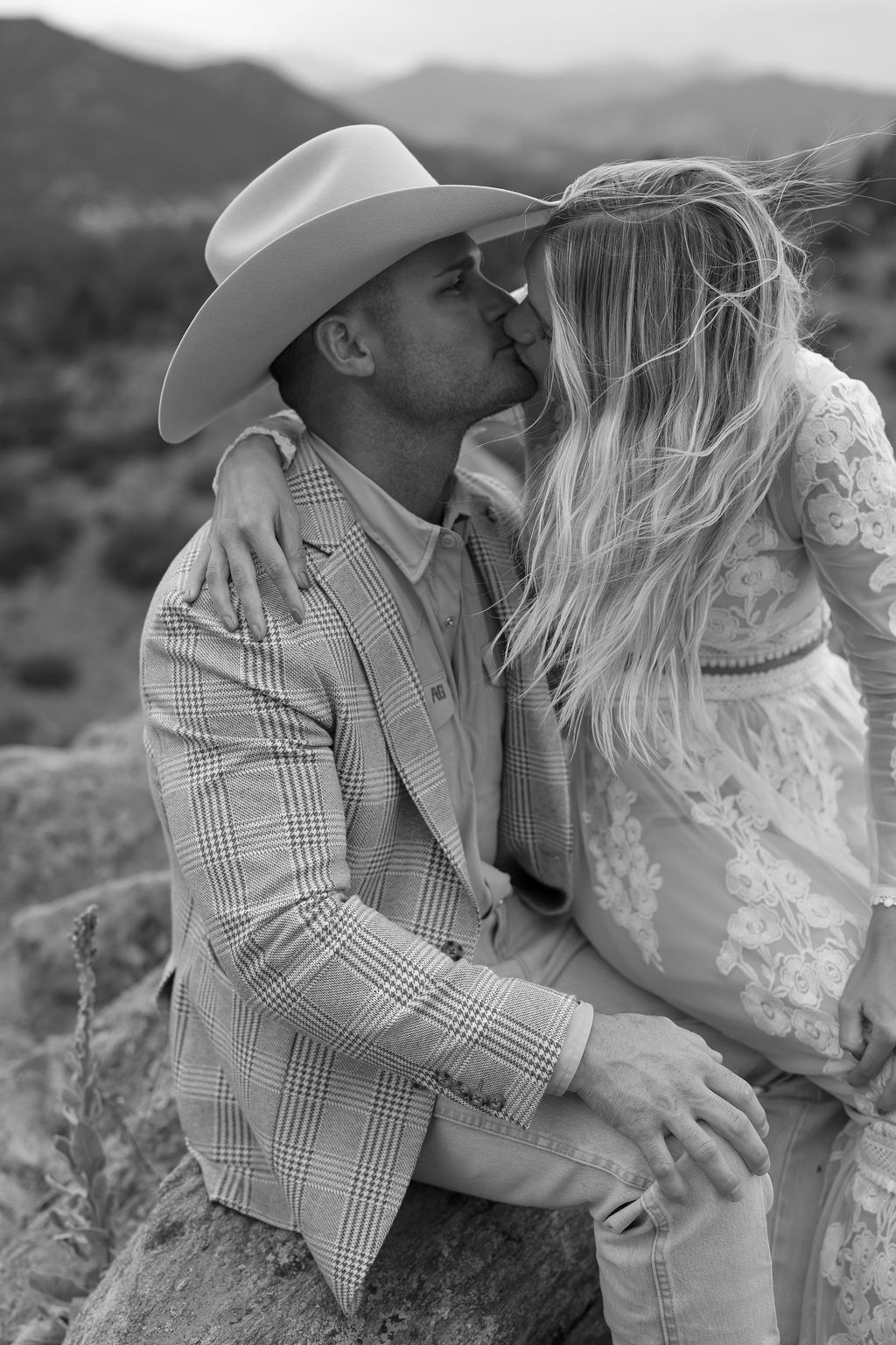 Mountain Chic Portrait Session with country chic attire and stormy weather at mount falcon west. Couple kisses at a rocky overlook with windblown hair