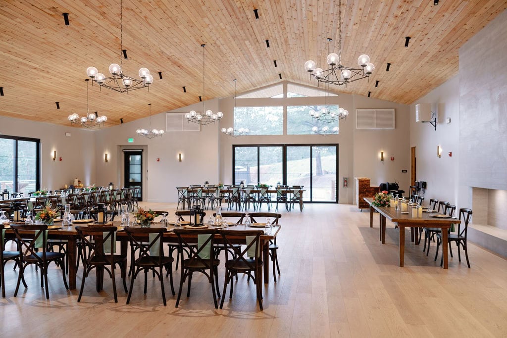 Mountain View Ranch Lakeview Reception Set Up with wooden tables and chairs with a clean and modern chic design utilizing lanterns and florals as centerpieces.
