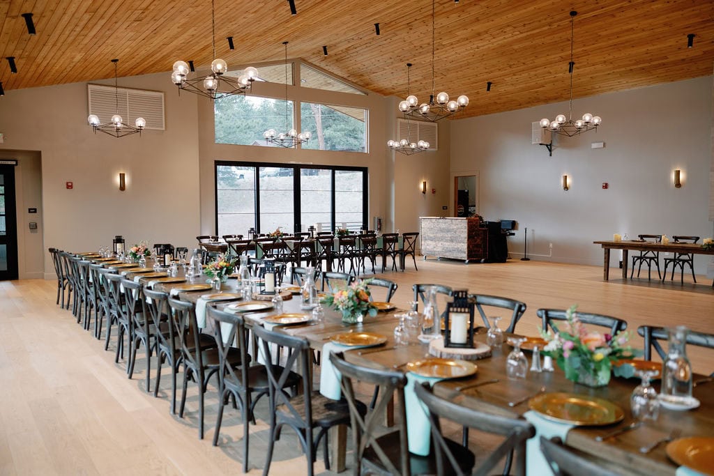 Mountain View Ranch Lakeview Reception Set Up with wooden tables and chairs with a clean and modern chic design utilizing lanterns and florals as centerpieces.