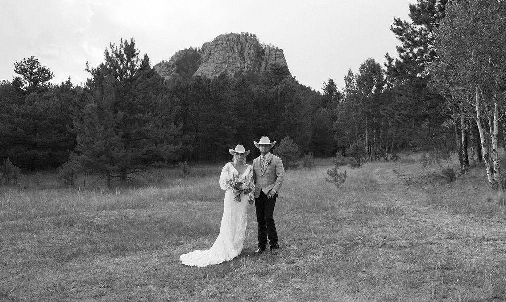 Western chic mountain view ranch wedding with a dramatic black and white of the bride and groom in front of a huge mountain cliff