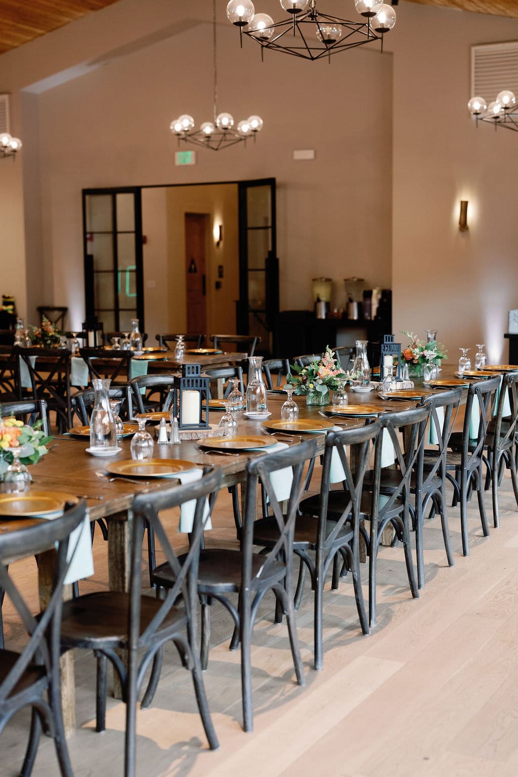 Mountain View Ranch Lakeview Reception Set Up with wooden tables and chairs with a clean and modern chic design utilizing lanterns and florals as centerpieces.