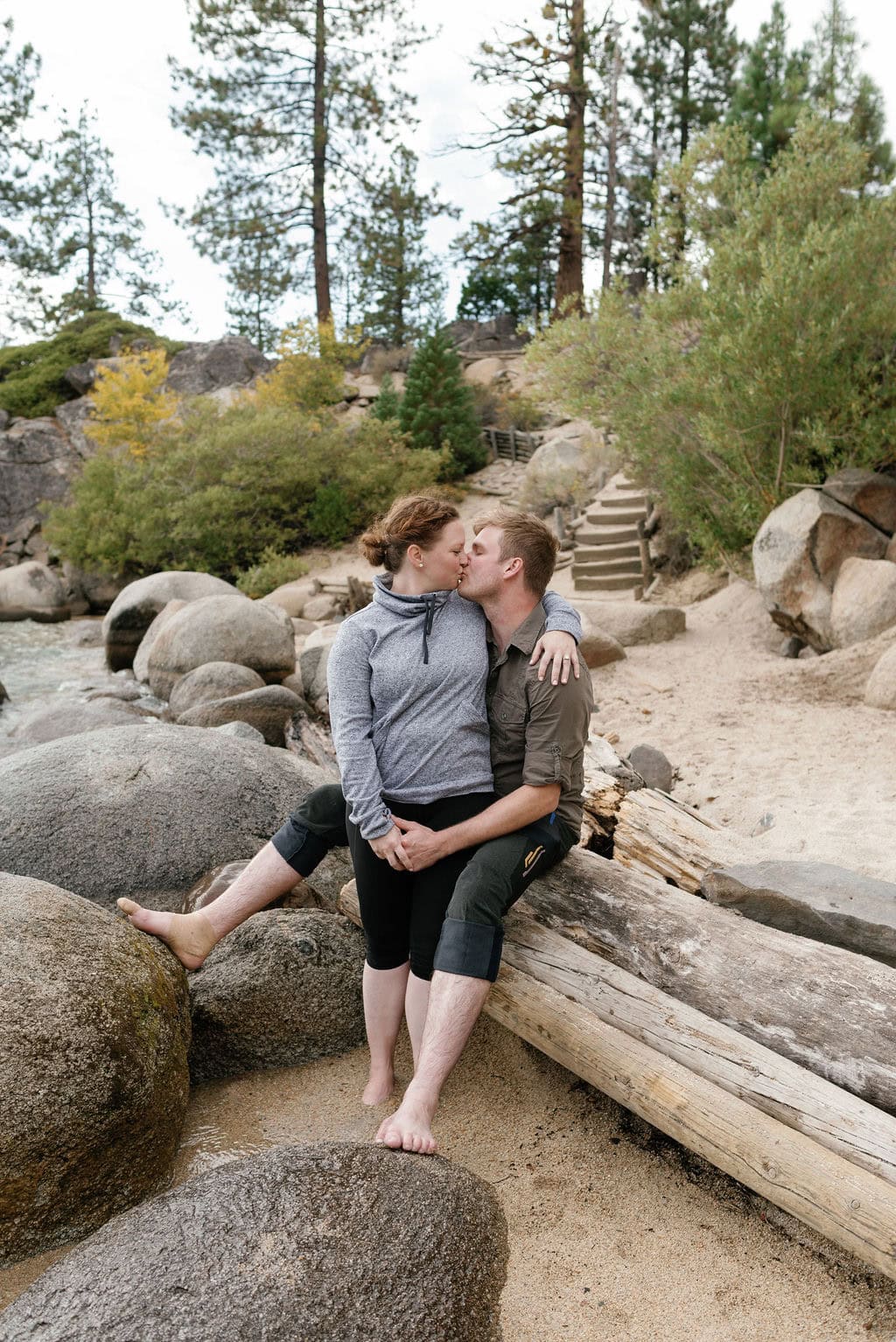 South Lake Tahoe Couples Portrait Session at secret cove on a windy fall afternoon. Couple sits on beached wood.