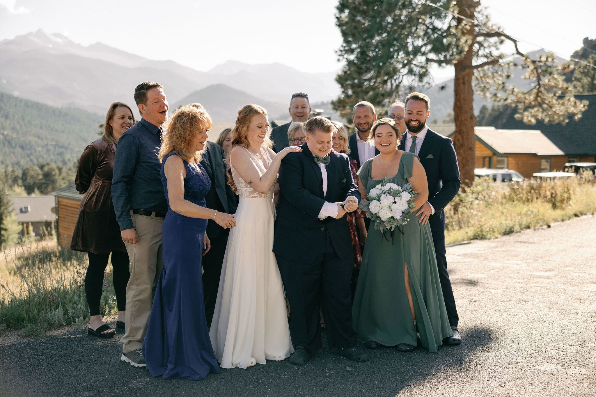 LGBTQ+ Couple celebrates their wedding in estes park colorado with their favorite people by popping champagne outside of their VRBO