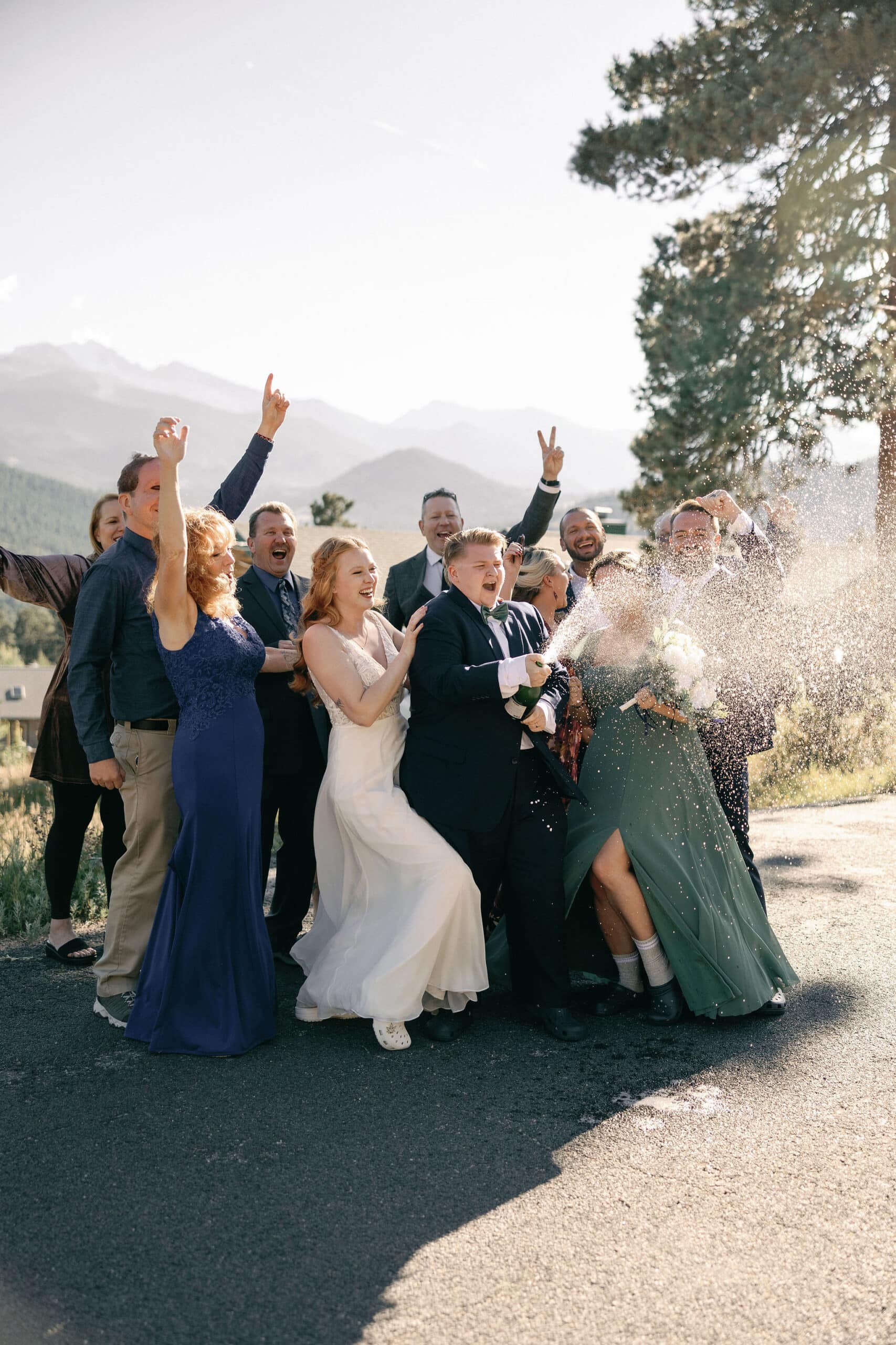 LGBTQ+ Couple celebrates their wedding in estes park colorado with their favorite people by popping champagne outside of their VRBO