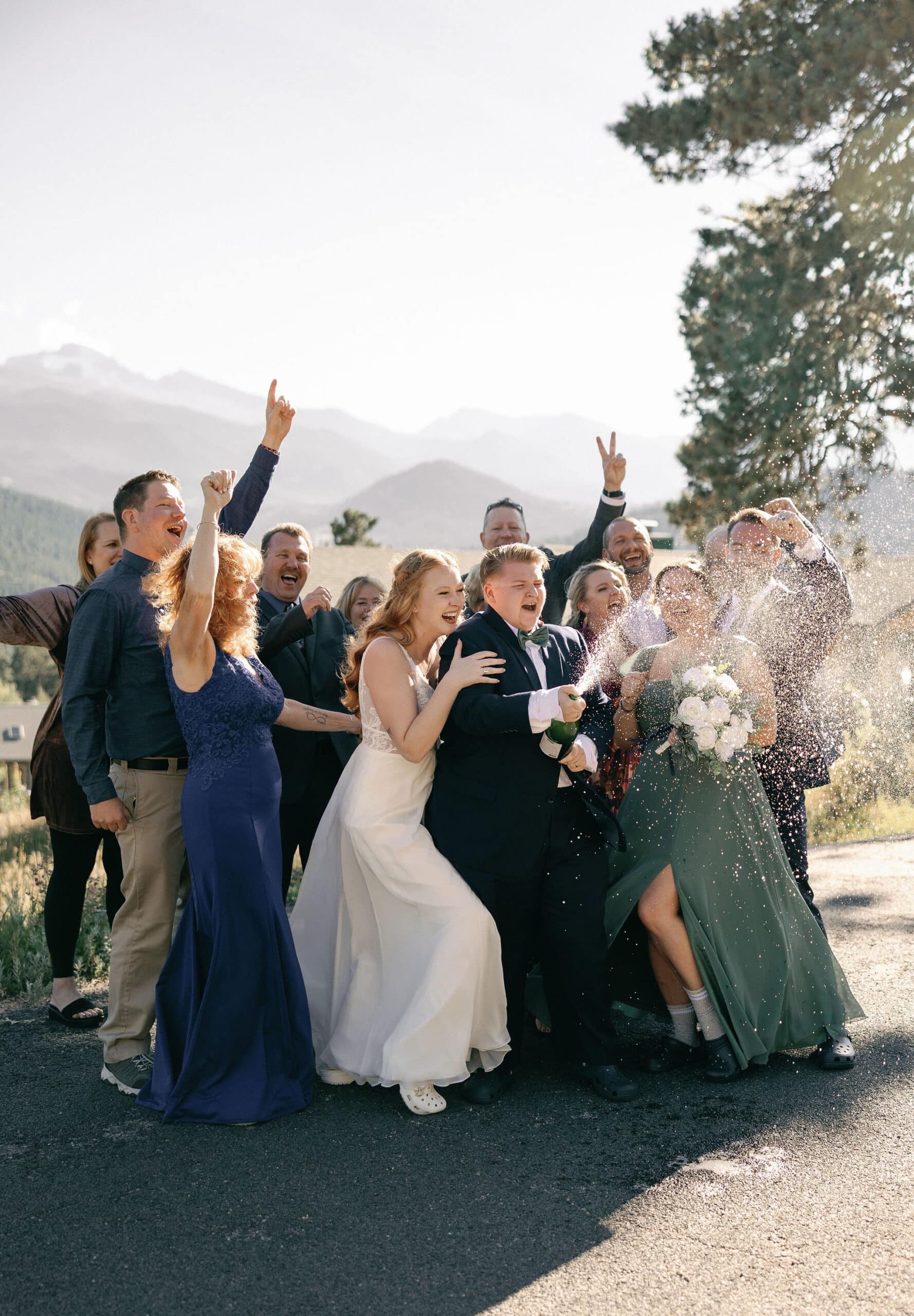 LGBTQ+ Couple celebrates their wedding in estes park colorado with their favorite people by popping champagne outside of their VRBO