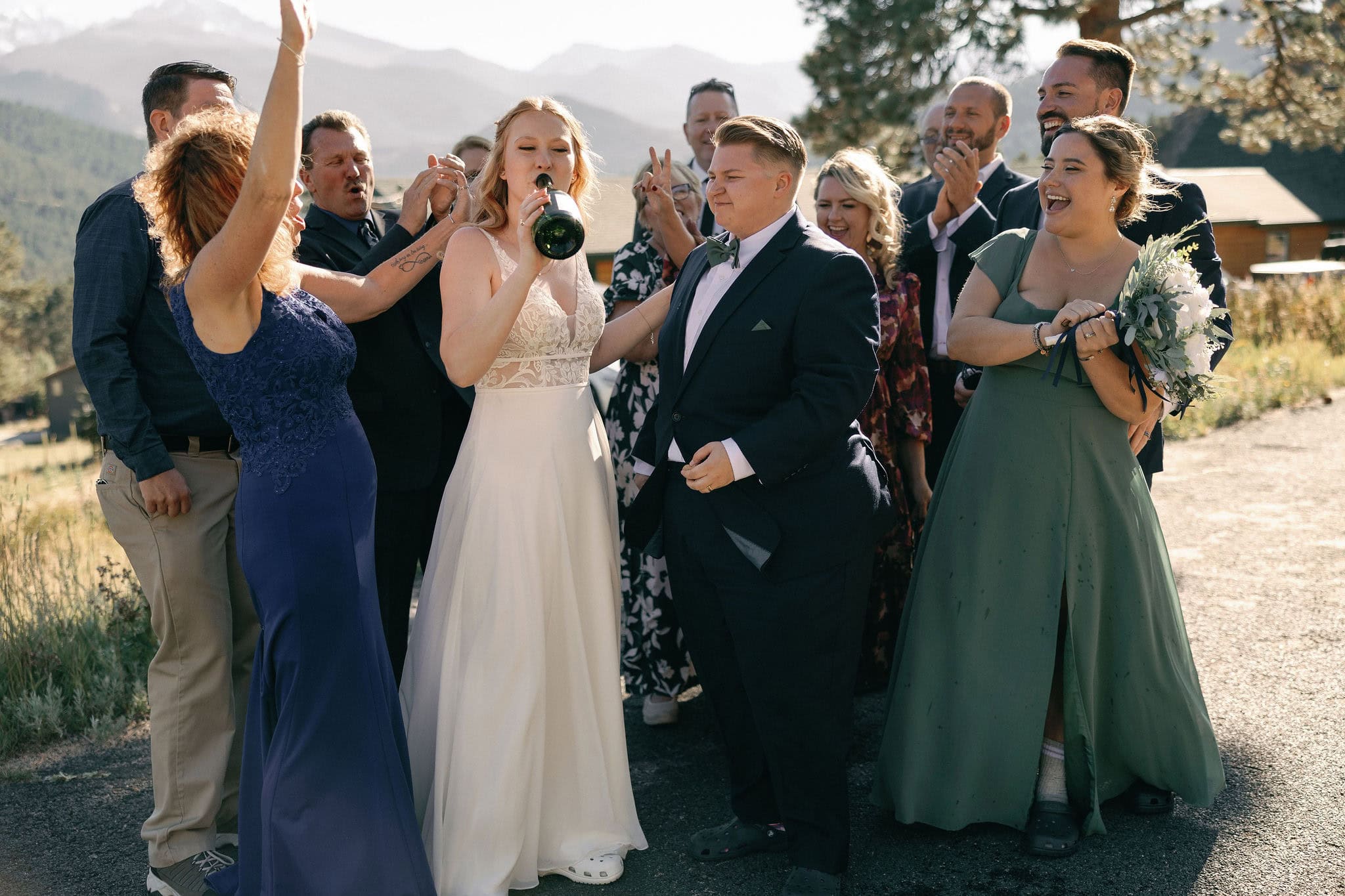 LGBTQ+ Couple celebrates their wedding in estes park colorado with their favorite people by popping champagne outside of their VRBO
