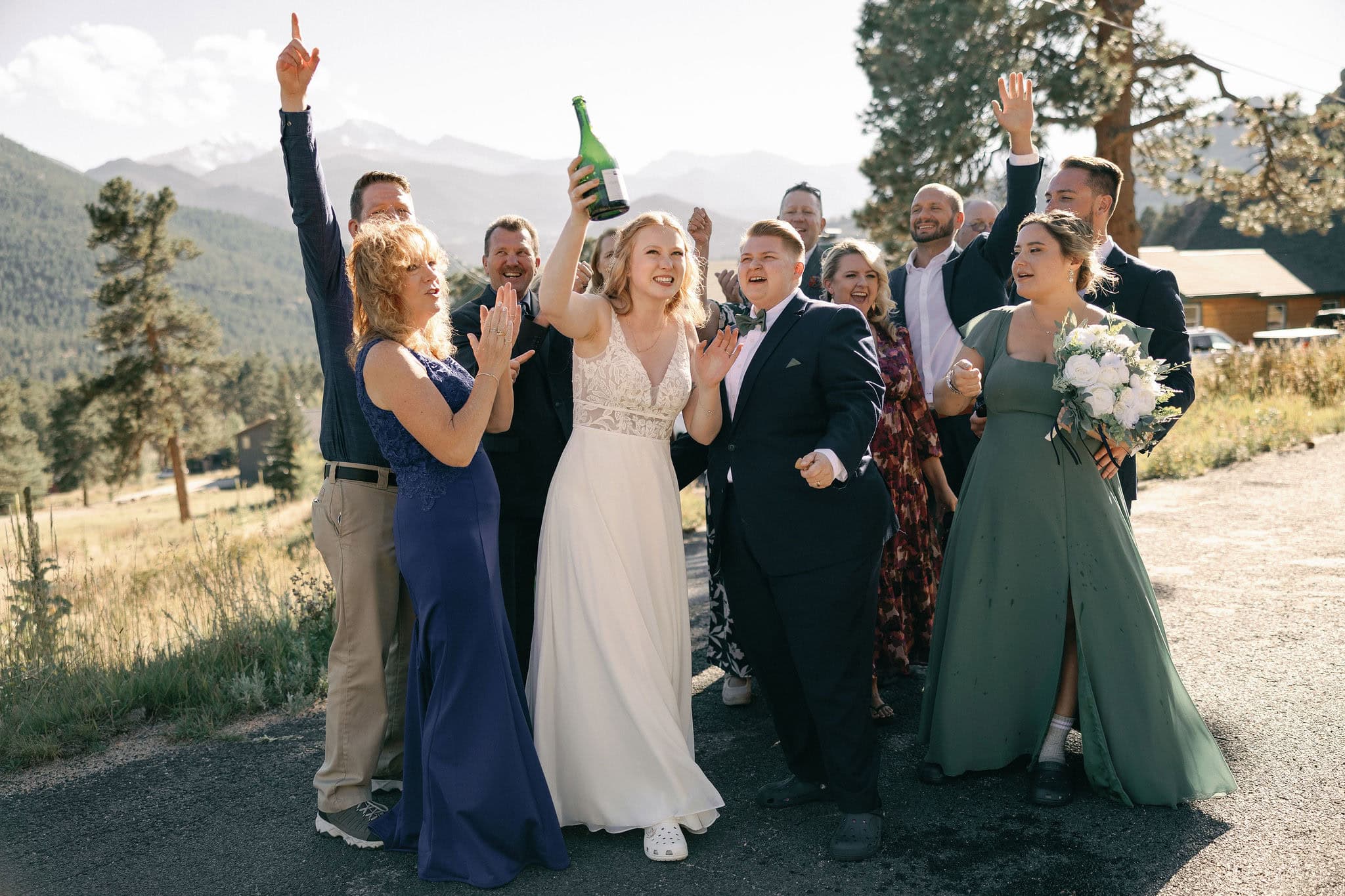LGBTQ+ Couple celebrates their wedding in estes park colorado with their favorite people by popping champagne outside of their VRBO
