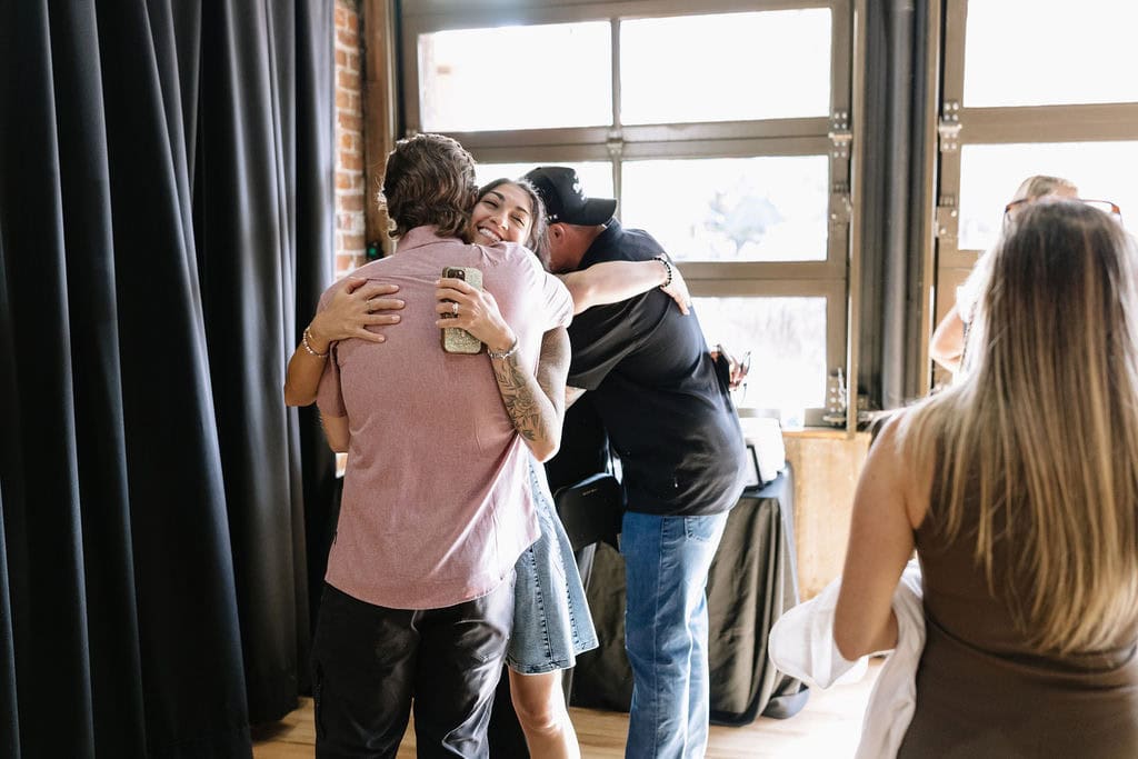 Emotional hugs and laughter captured during a Colorado wedding welcome party at The Rose