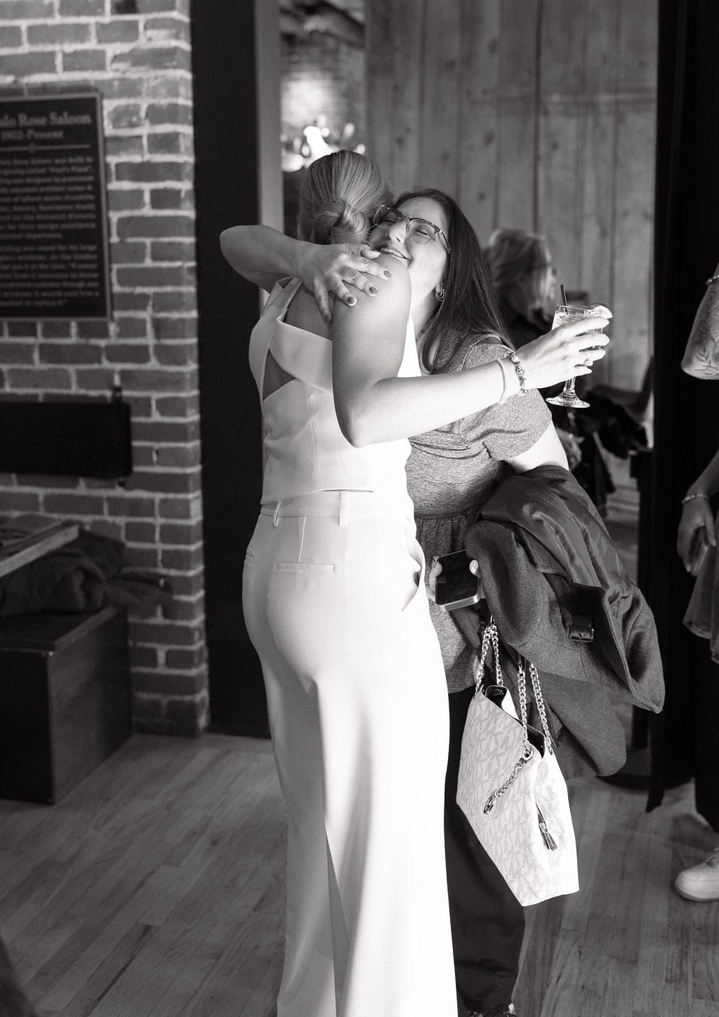 Emotional hugs and laughter captured during a Colorado wedding welcome party at The Rose