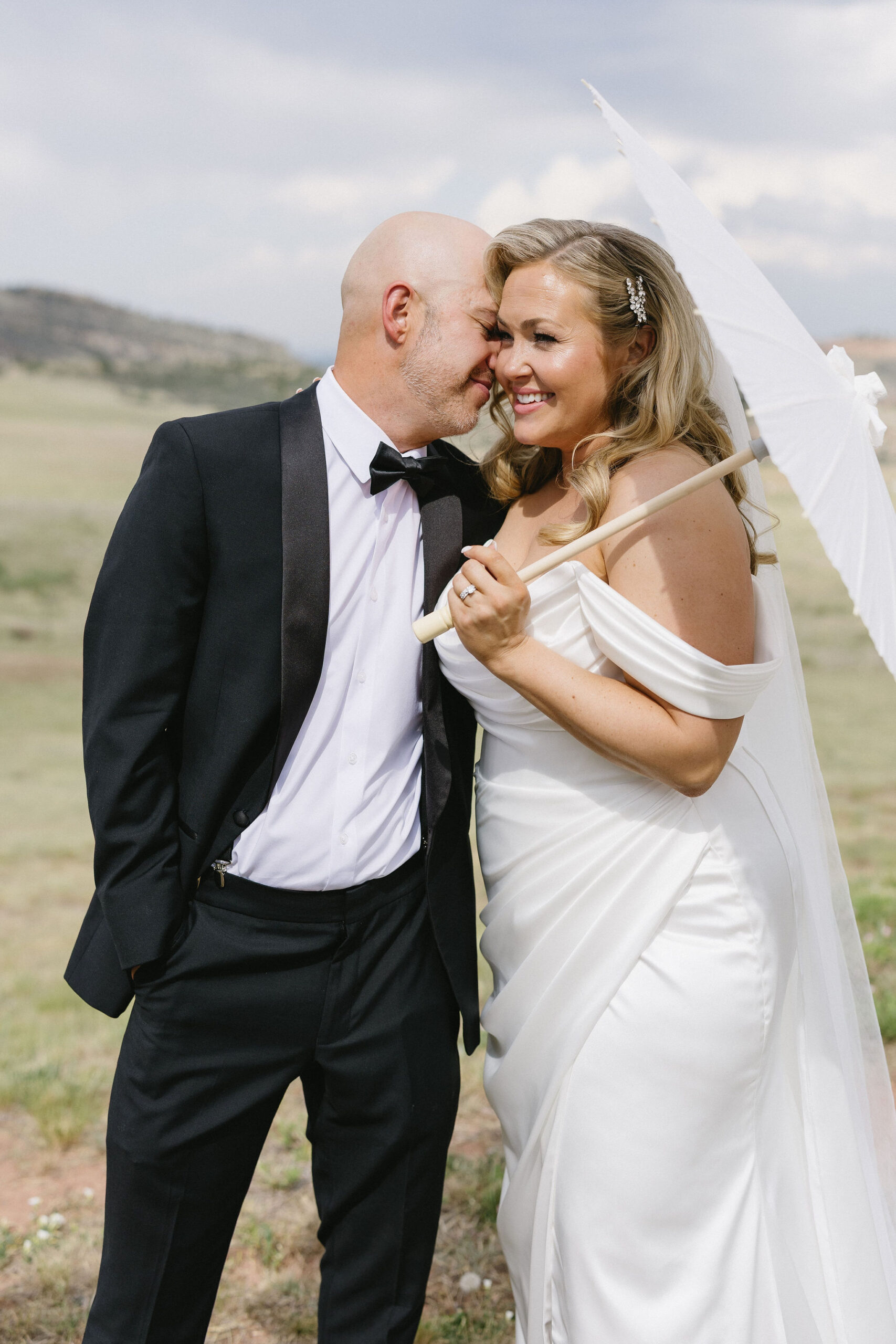 Bride and groom romantic and classy portraits in the bright colorado sunshine with a parasol at The Fort Restaurant in Morrison, CO.