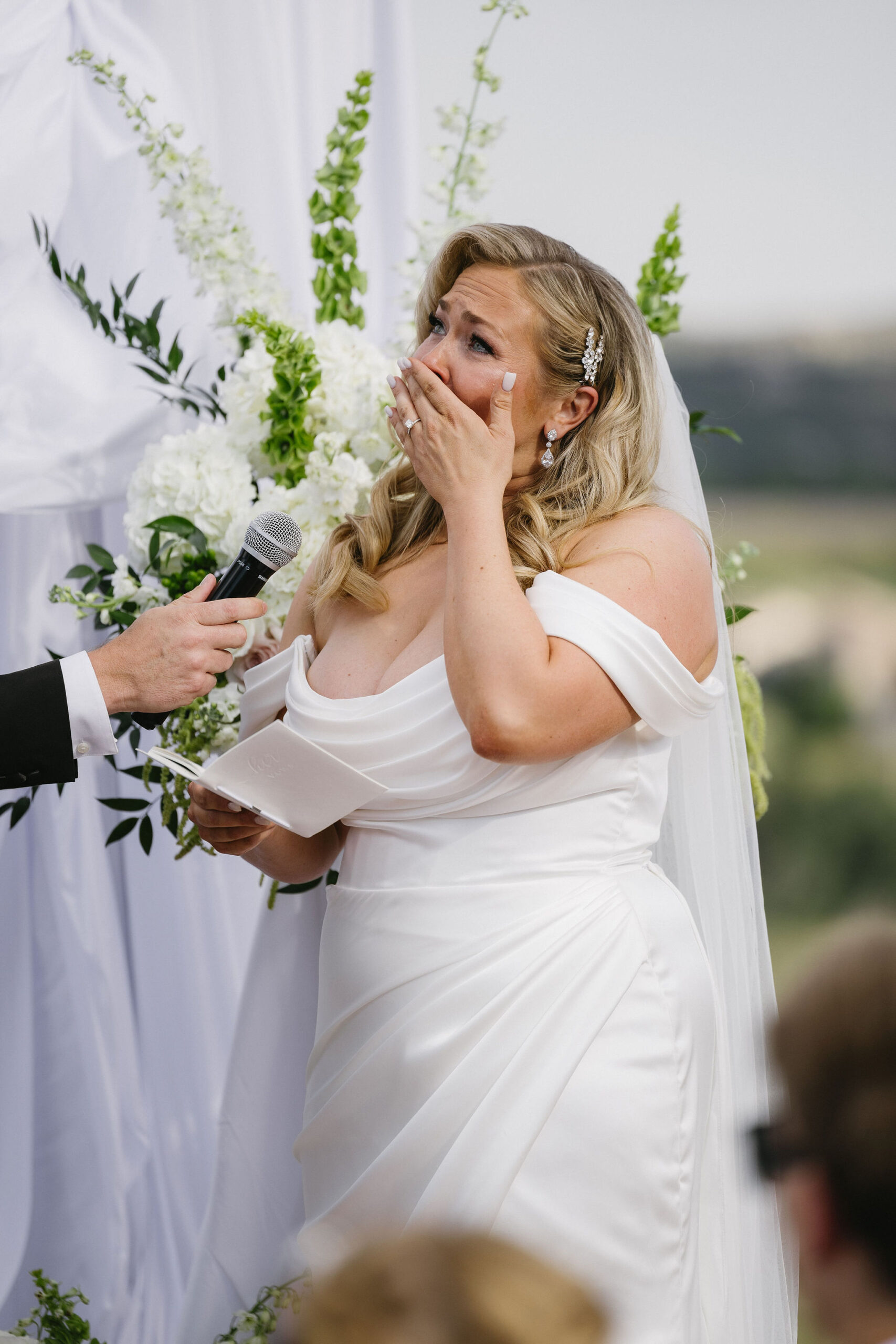 Bride cries while reading her vows at their Romantic and Bright wedding ceremony on the helipad outside of The Fort Morrison Colorado Restaurant 